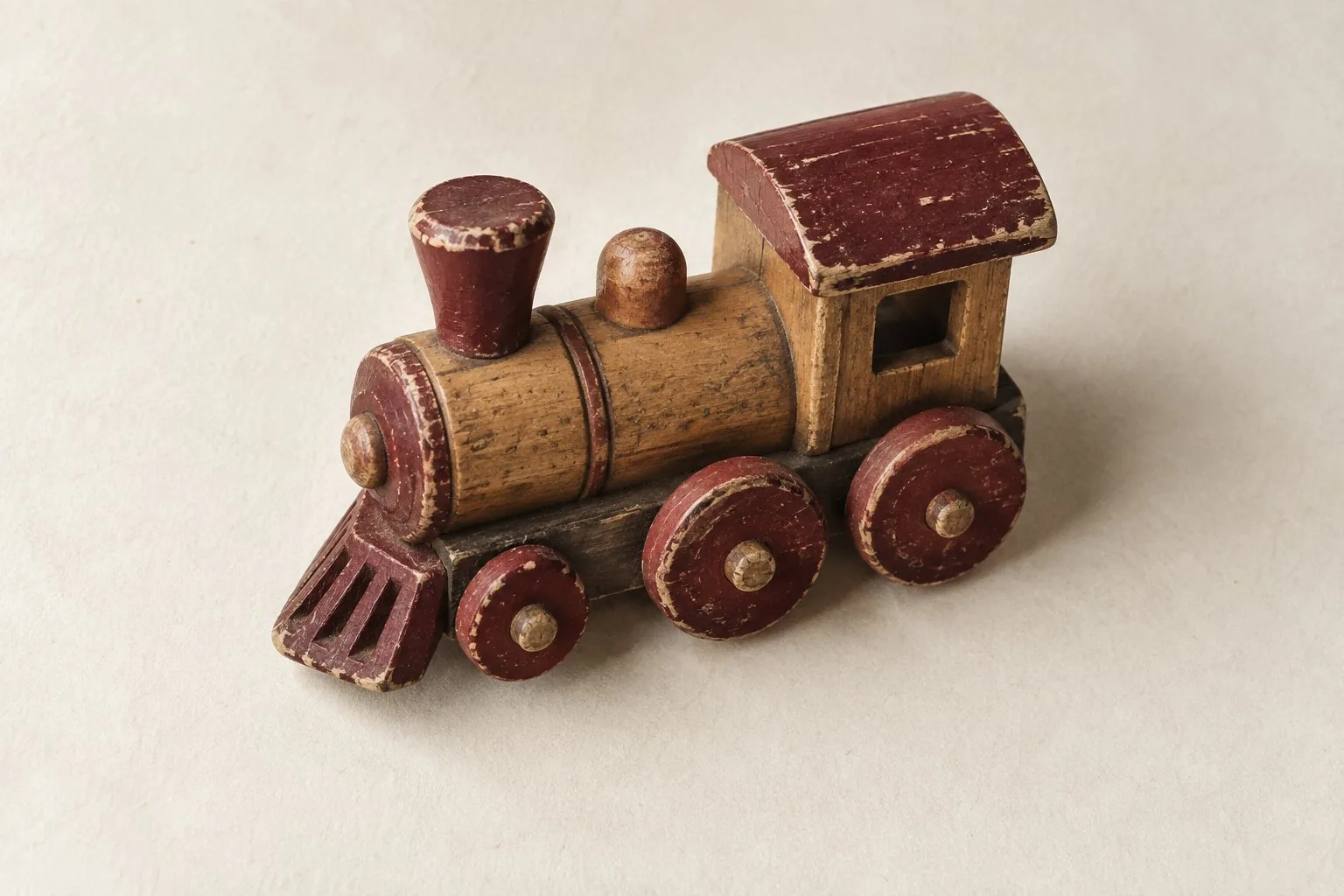 Une petite locomotive en bois usé aux roues bordeaux